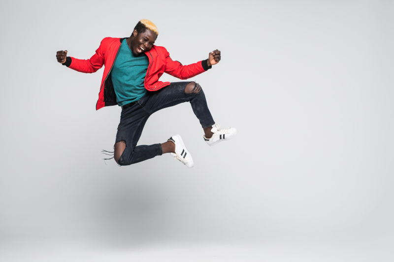 一位快乐的黑人男子在白色背景下跳跃的全景画像