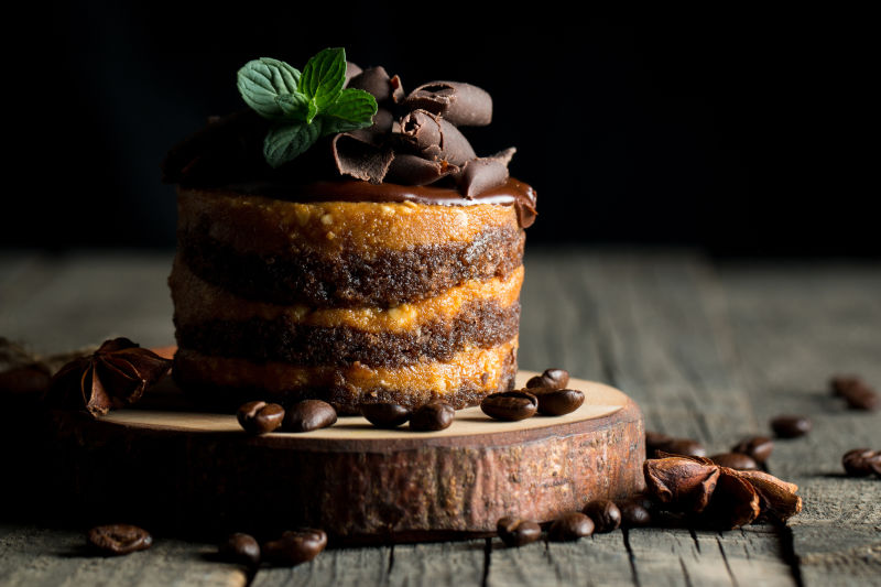 黑石板上的巧克力蛋糕配薄荷-黑底咖啡豆-特写照片-新鲜可口的甜点食品概念