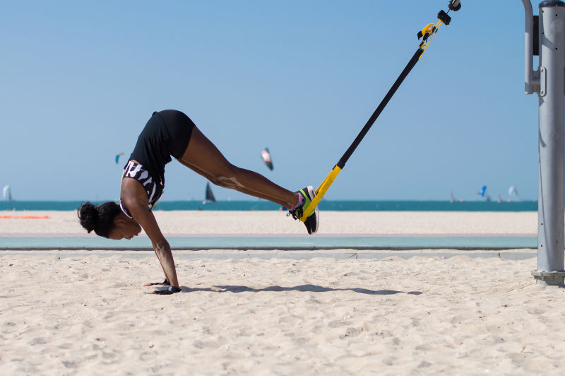 联合酋长国迪拜海滩一名年轻的非洲妇女在用绳索进行悬吊训练时进行了困难的运动