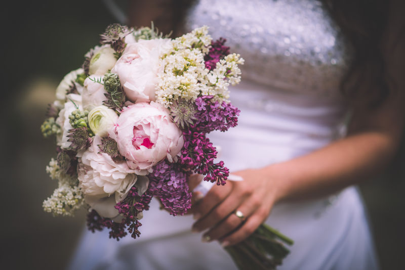 新娘手上的粉色和紫色婚礼花束婚礼当天牡丹和丁香婚礼
