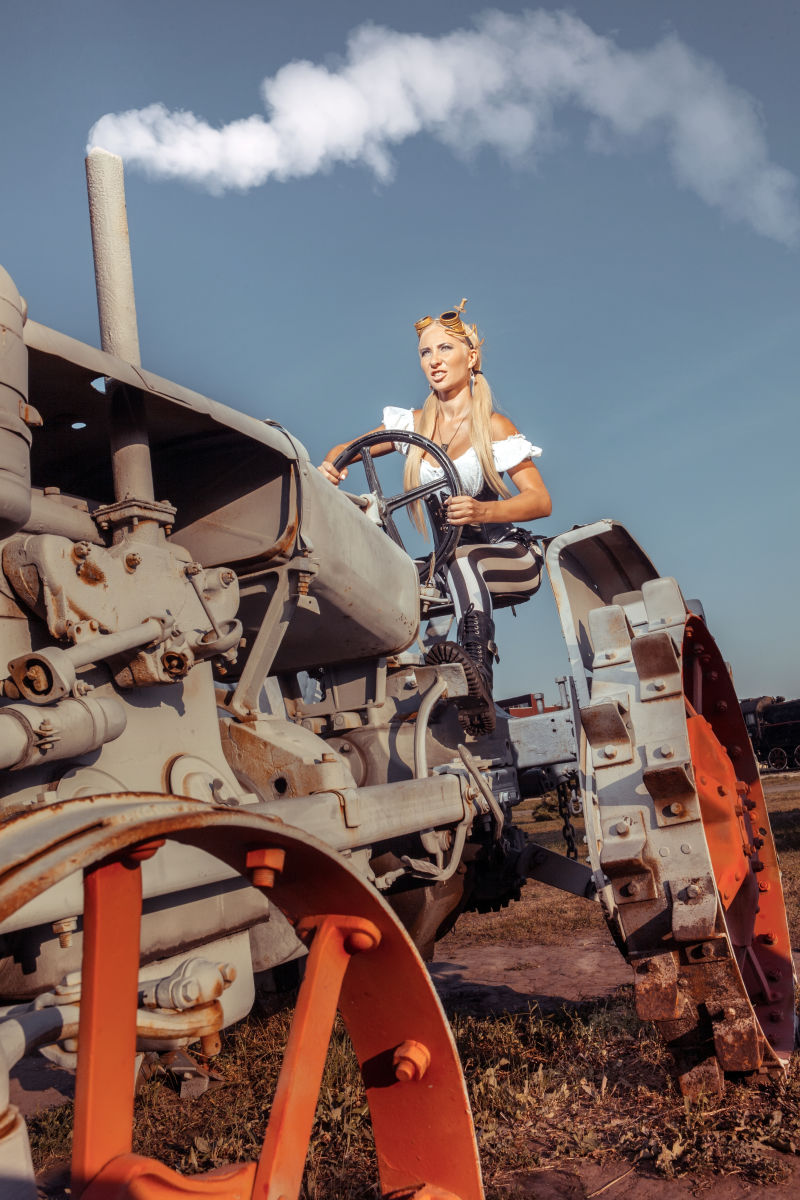 穿蒸汽朋克衣服的性感女人开着老式拖拉机