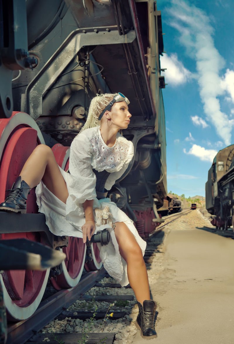 穿着复古服装的女人坐在机车的轮子上