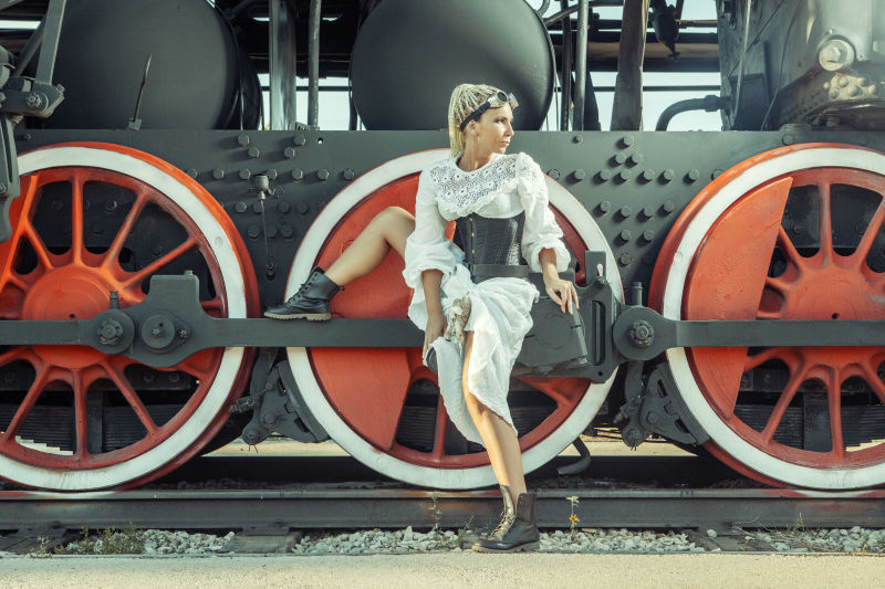 穿着复古服装的女人坐在机车的轮子上