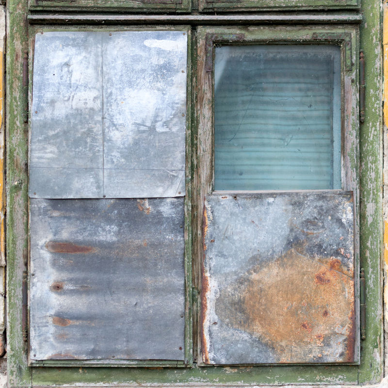 一栋生锈的绿色旧建筑阁楼上的观察窗