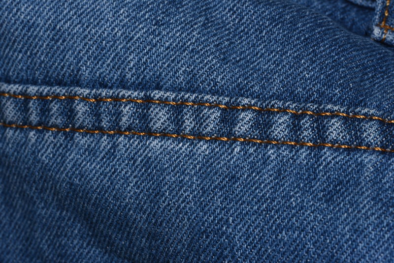 蓝色牛仔布牛仔裤纹理细节与接缝特写视图-经典的时尚牛仔裤-自然图案-有许多接缝-简单的画布-空的深蓝色牛仔布背景-用于复制空间