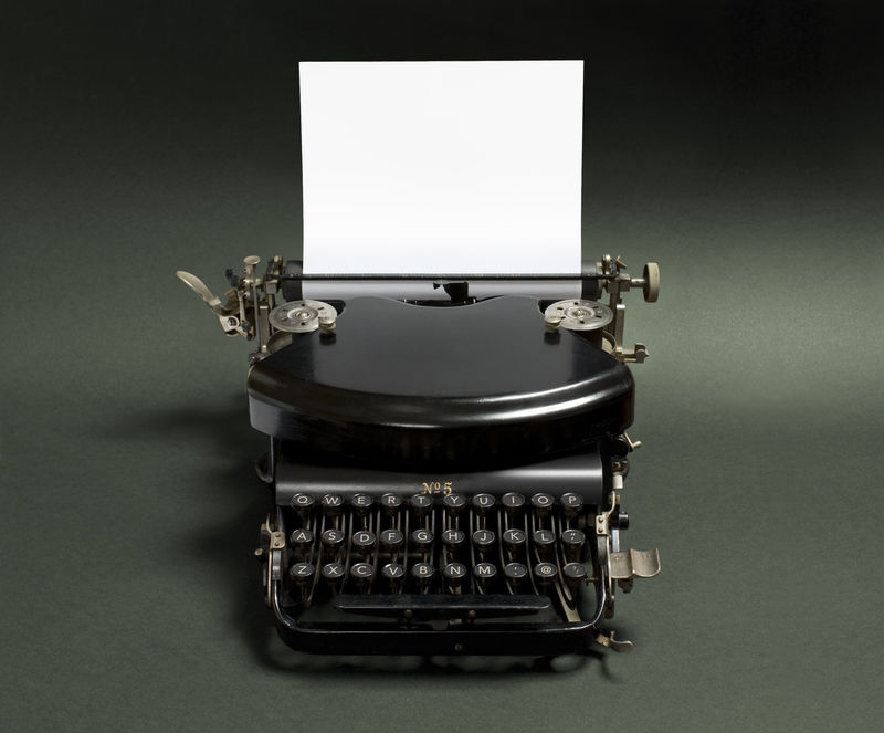 黑色背景的老式打字机-一种集成在黑色背景上的古打字机的低调版本-在白页上留有文本空间-复制空间上的灯光效果