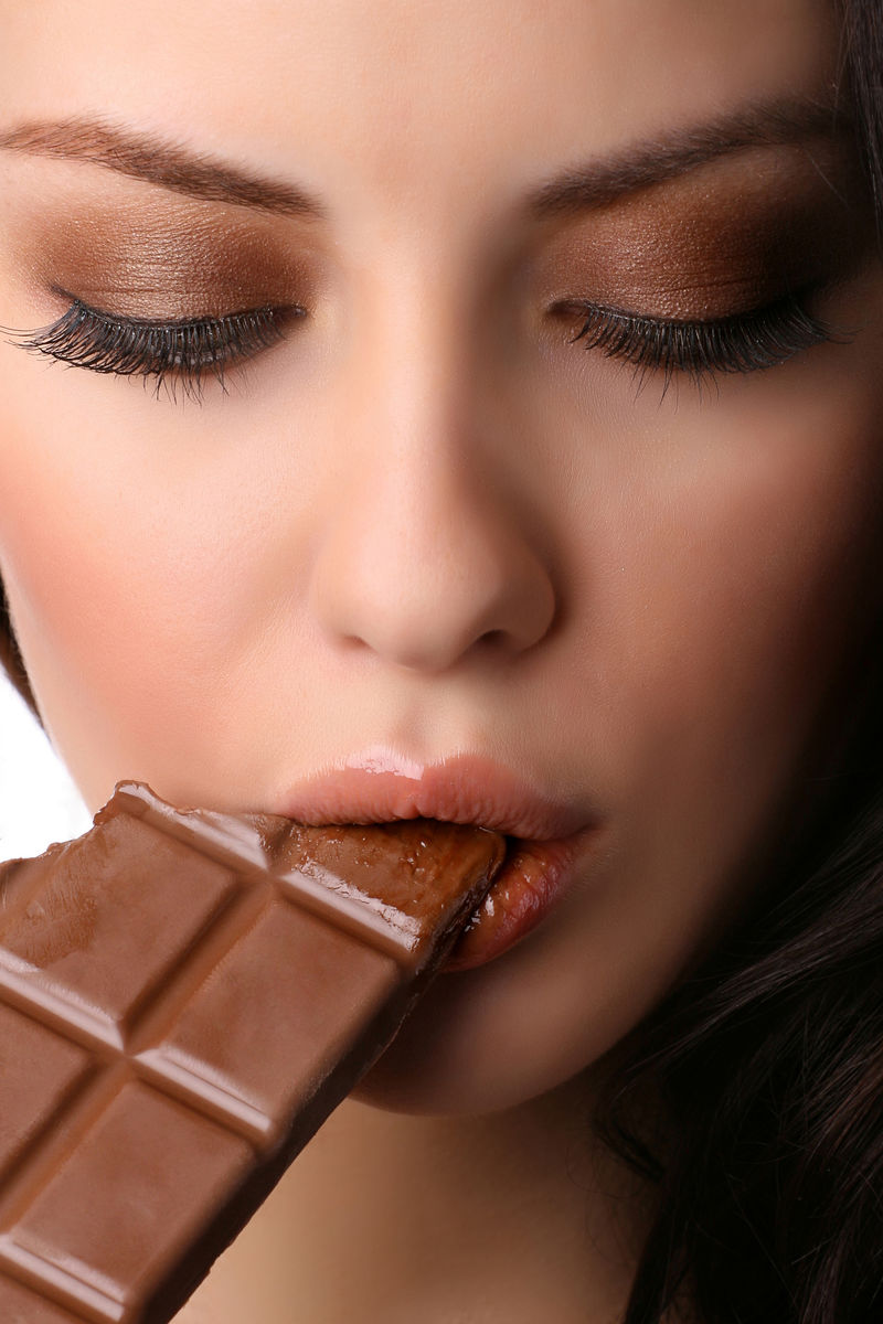 女性面部咬牛奶巧克力的特写镜头