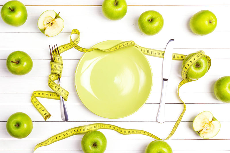饮食概念桌-配有餐具黄色卷尺和白木桌上的青苹果-减肥和健康
