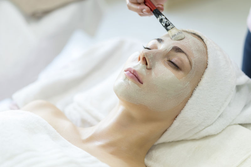 美丽的白人妇女戴着面具-躺在温泉浴场上-水疗沙龙的面部护理