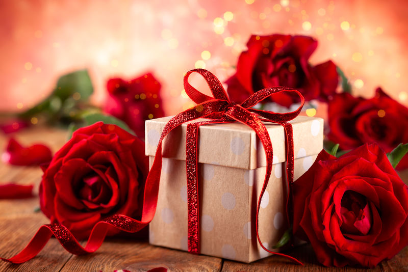 带红丝带蝴蝶结和红玫瑰的礼品盒
