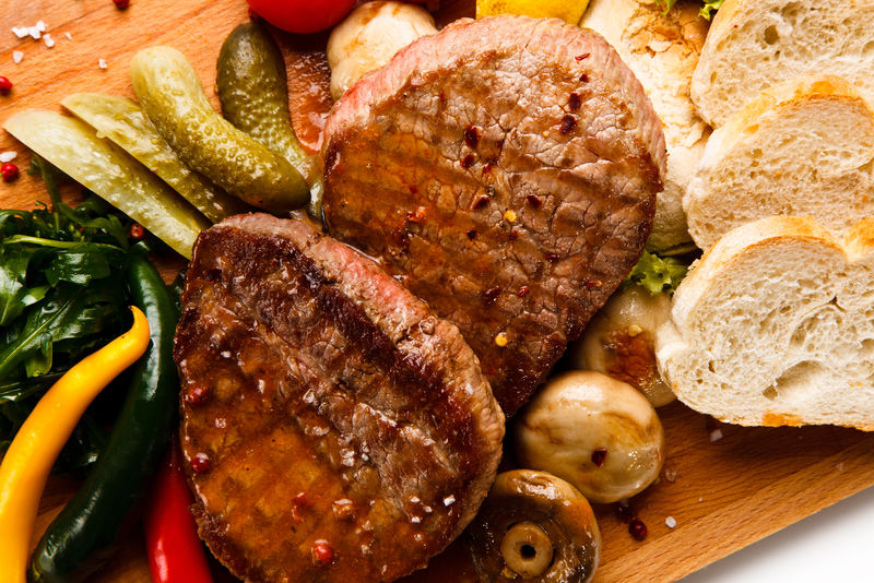 白底切肉板烤牛排和蔬菜