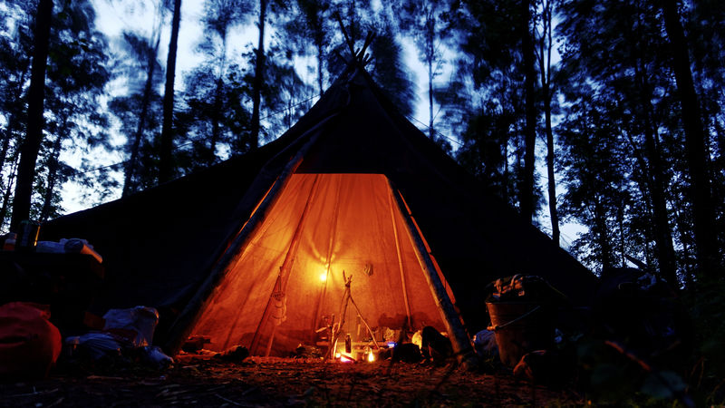 带油灯和营火的舒适的蒂皮在黑暗和暴风雨的森林里
