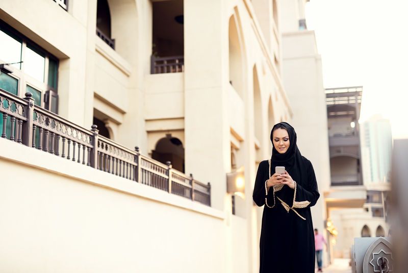 穆斯林妇女走路和打字信息