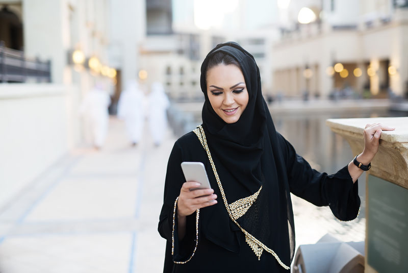 阿拉伯妇女用智能手机打字微笑着