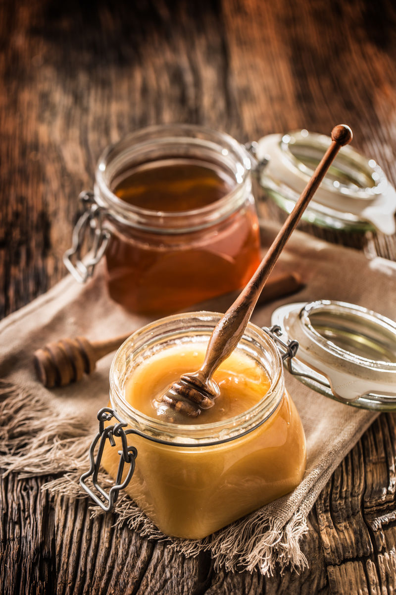 罐里的蜂蜜和乡村橡木桌上的勺