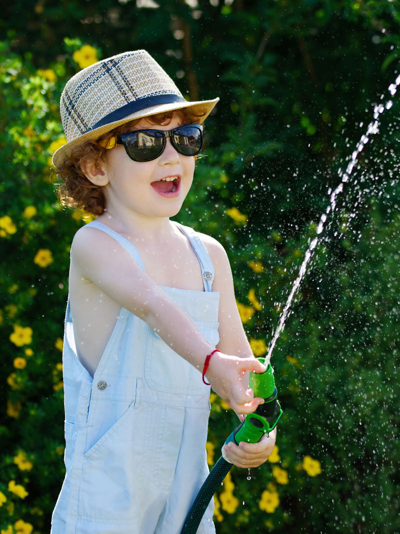 小男孩用软管给花园浇水