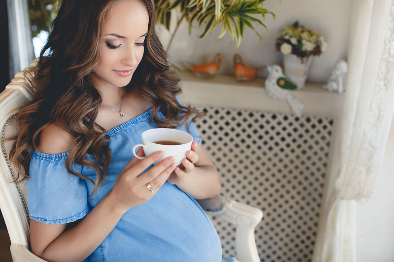 一个年轻的怀孕妇女喝了一杯茶