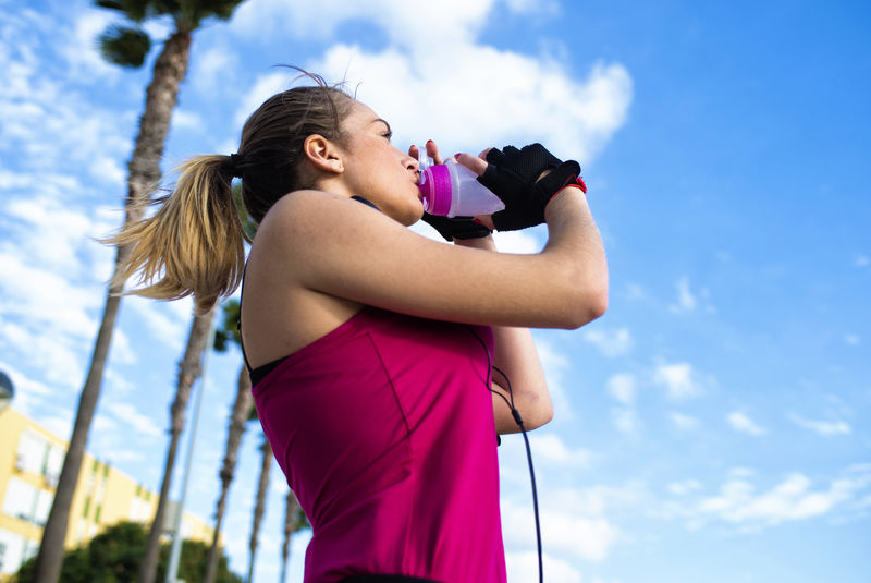 年轻的金发女运动员跑步后喝水