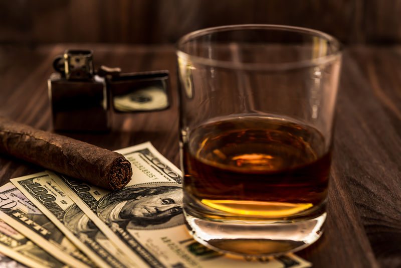 一杯威士忌酒一块钱一支古巴雪茄和一个木制桌子上的打火机视角聚焦古巴雪茄