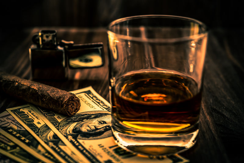 一杯威士忌酒一块钱一支古巴雪茄和一个木制桌子上的打火机角度视图聚焦古巴雪茄图像渐晕和橙蓝色调