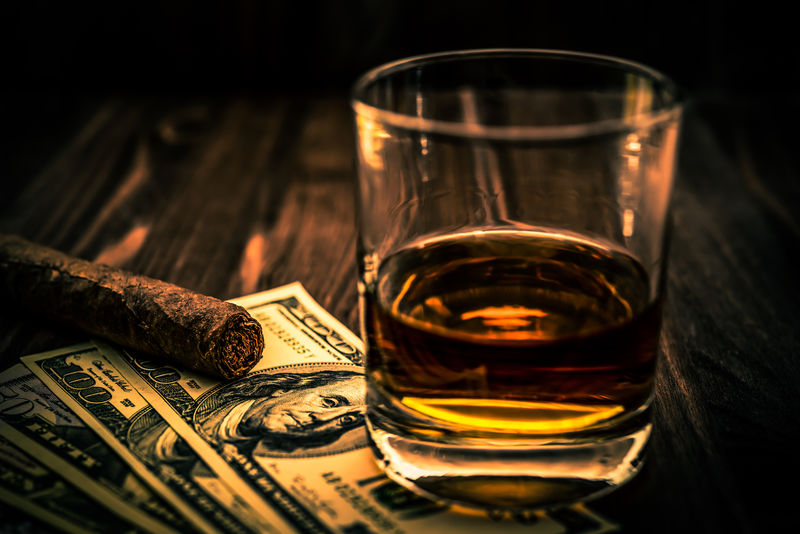 一杯威士忌酒和一张放在木桌上的古巴雪茄钱角度视图聚焦古巴雪茄图像渐晕和橙蓝色调