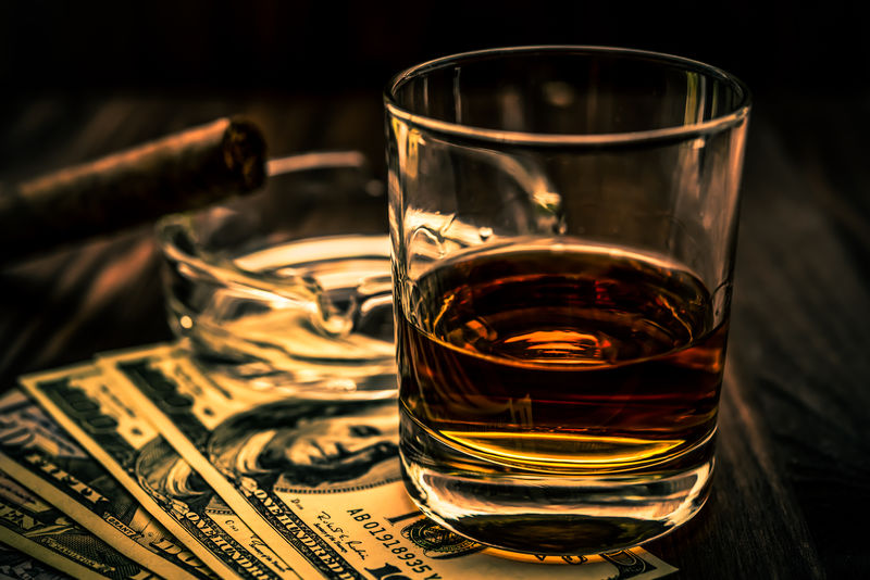 一杯威士忌酒和一张放在木桌上的古巴雪茄钱角度视图浅景深聚焦威士忌玻璃图像渐晕和橙蓝色调