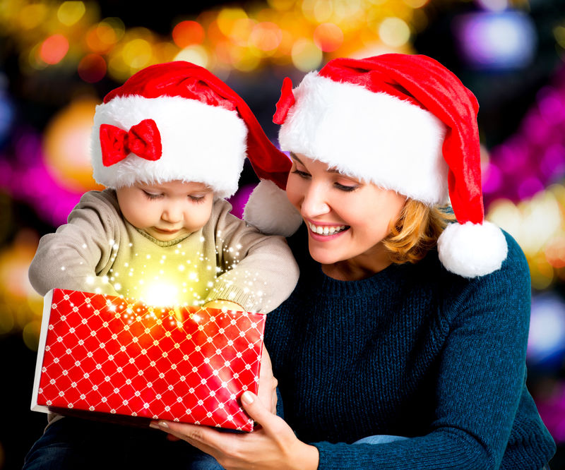 带着小孩的母亲在圣诞节打开装有礼物的盒子