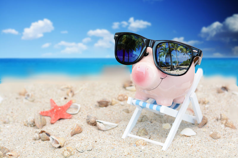 带太阳镜的小猪存钱罐-放在躺椅上-为度假概念节省开支