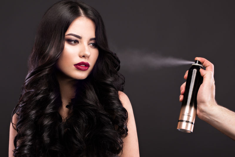 美丽的黑色卷发经典模型：化妆和红色的嘴唇和一瓶护发产品美人脸