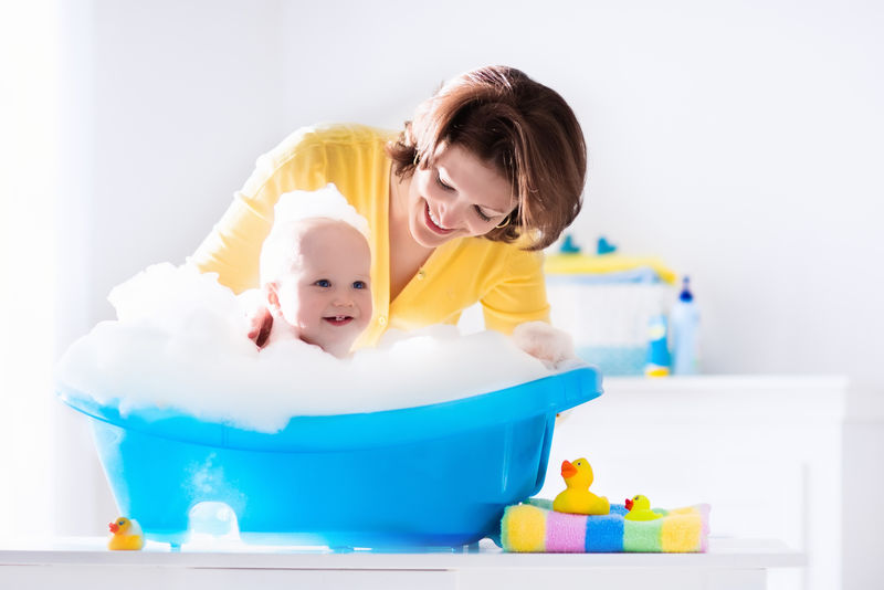 年轻的母亲正在洗澡的男婴
