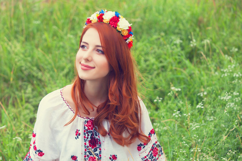 在绿草上穿着乌克兰服装的红头发女孩