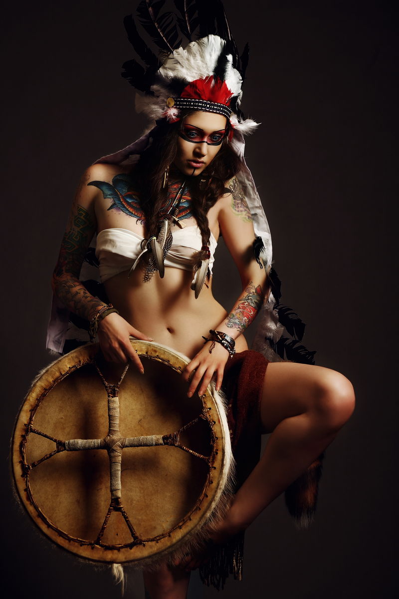 穿着美国土著服装的漂亮女人头上顶着蟑螂在画室里摆姿势