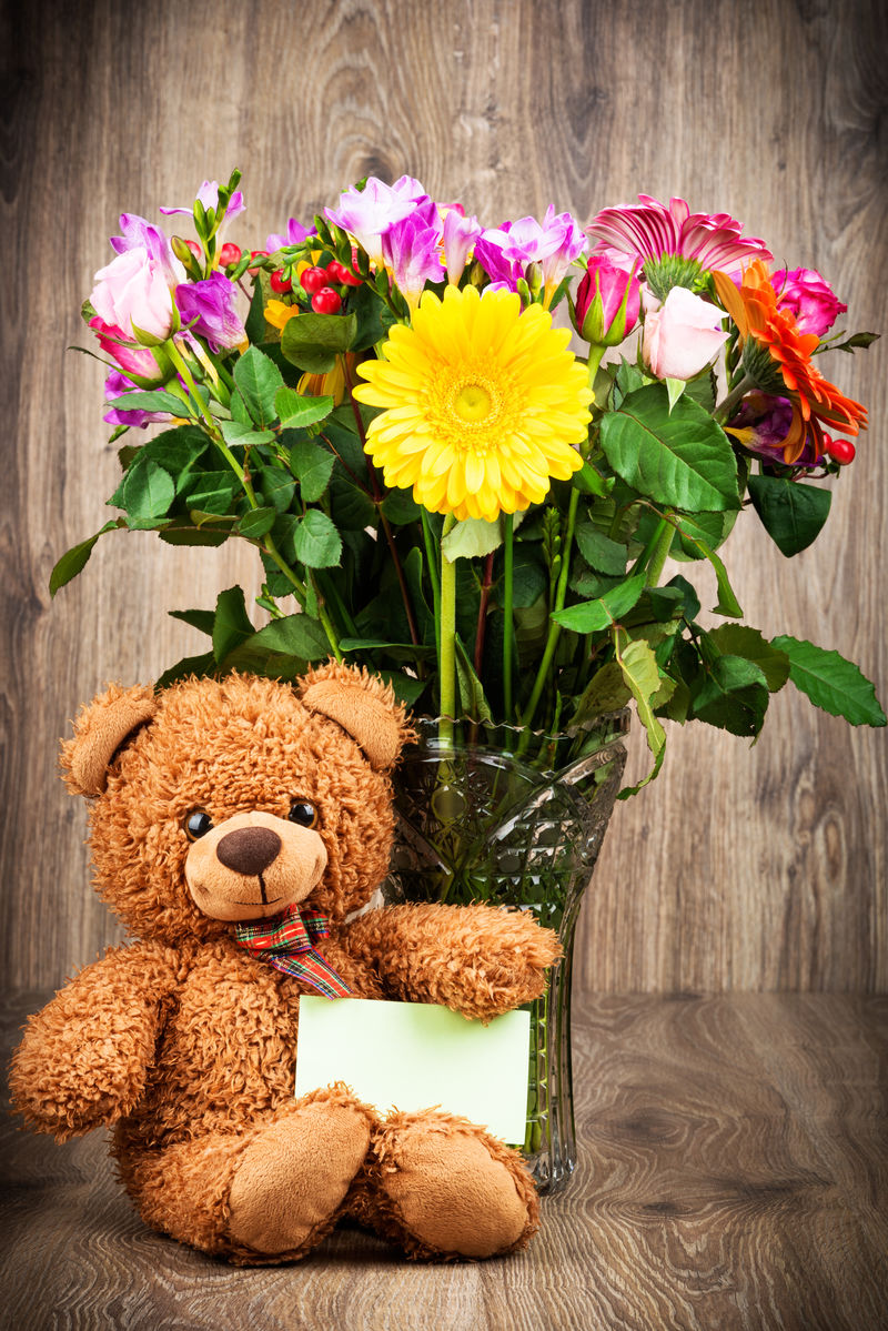 漂亮的花和木制背景的泰迪熊