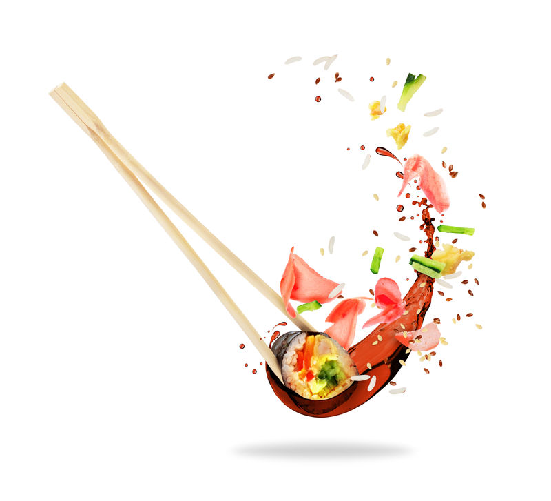 夹在筷子之间的一块寿司上面洒着酱油呈白色背景