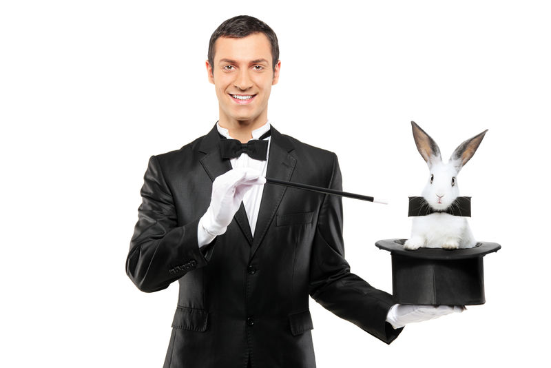 一个穿着黑西装的魔术师拿着顶帽子帽子里有一只兔子