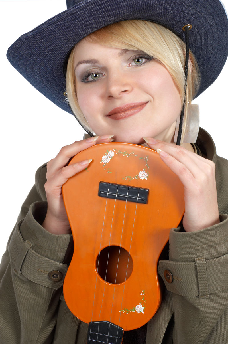 可爱的金发女牛仔拿着橙色的小吉他