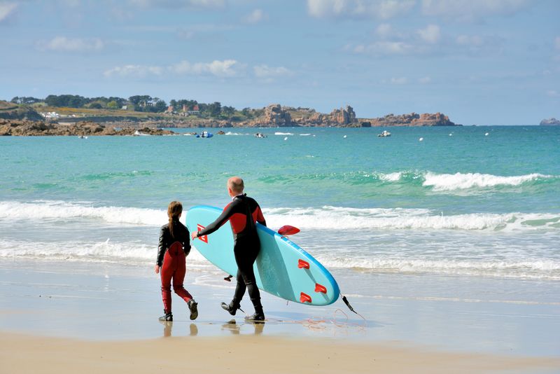 父亲和女儿在布列塔尼的一个海滩上行走他们刚刚在那里练习冲浪