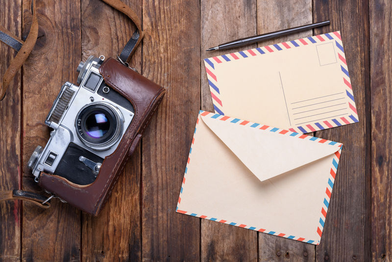 老式信封旧木桌上有明信片和复古照相机