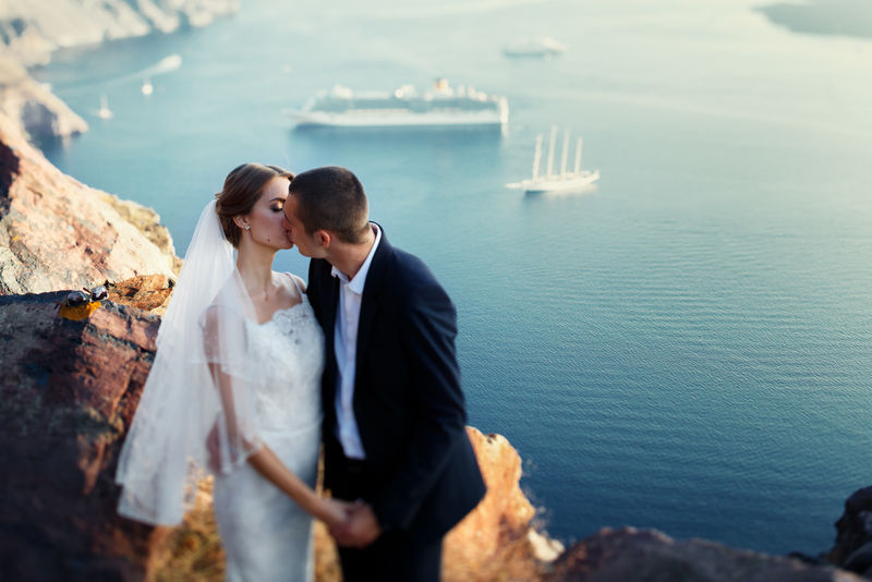 新郎新娘在日落时分在山海和船上接吻