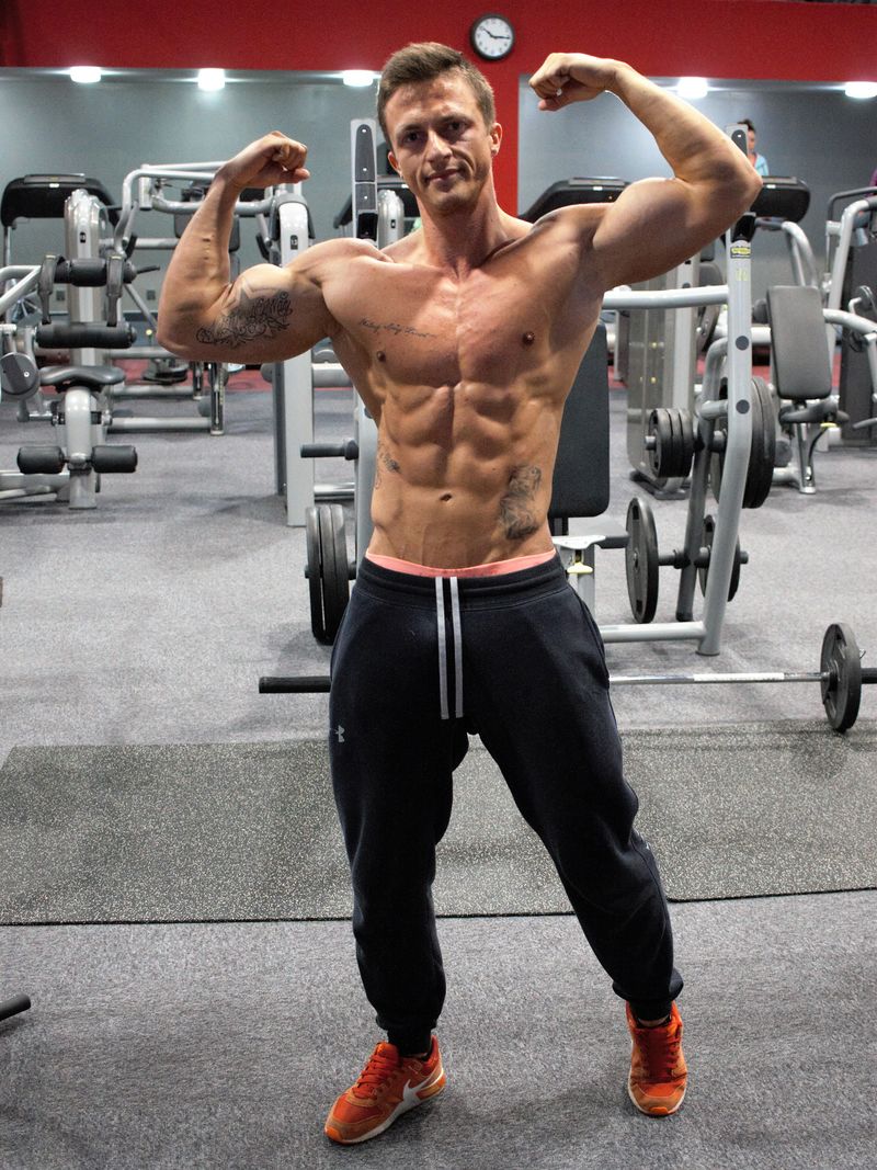 一个身体健康的男人在健身房展示他训练有素的身体的照片