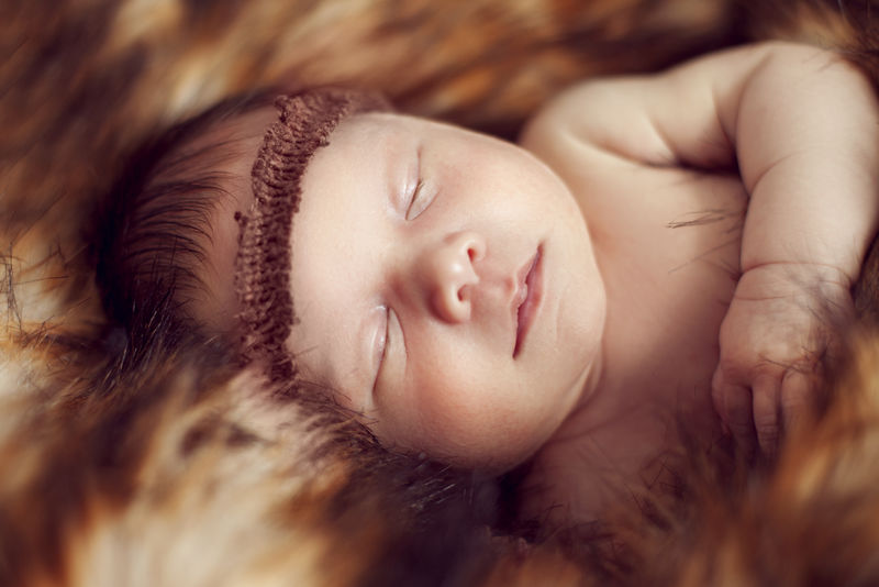 新生婴儿在红色毛皮上安睡概念家庭