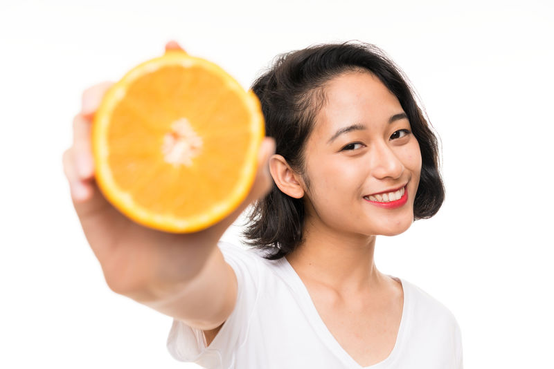 亚洲年轻女子背景孤立手拿橘子