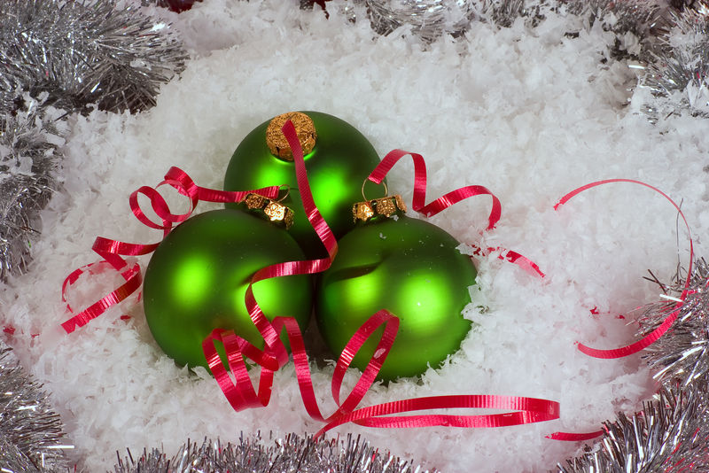 三件绿色圣诞装饰品一堆雪堆戴着银色花环