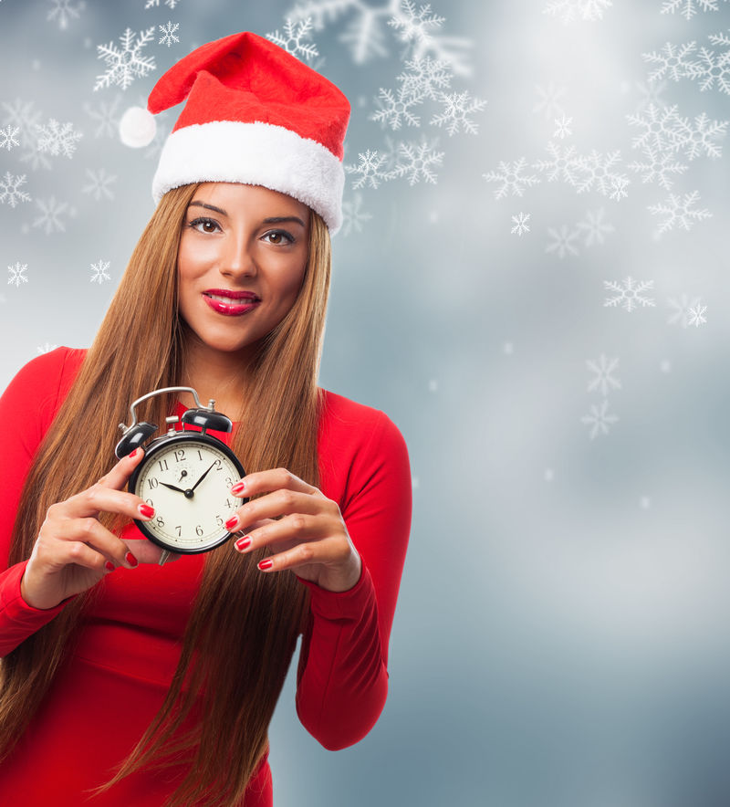一位美丽的年轻女子在圣诞节拿着闹钟的画像