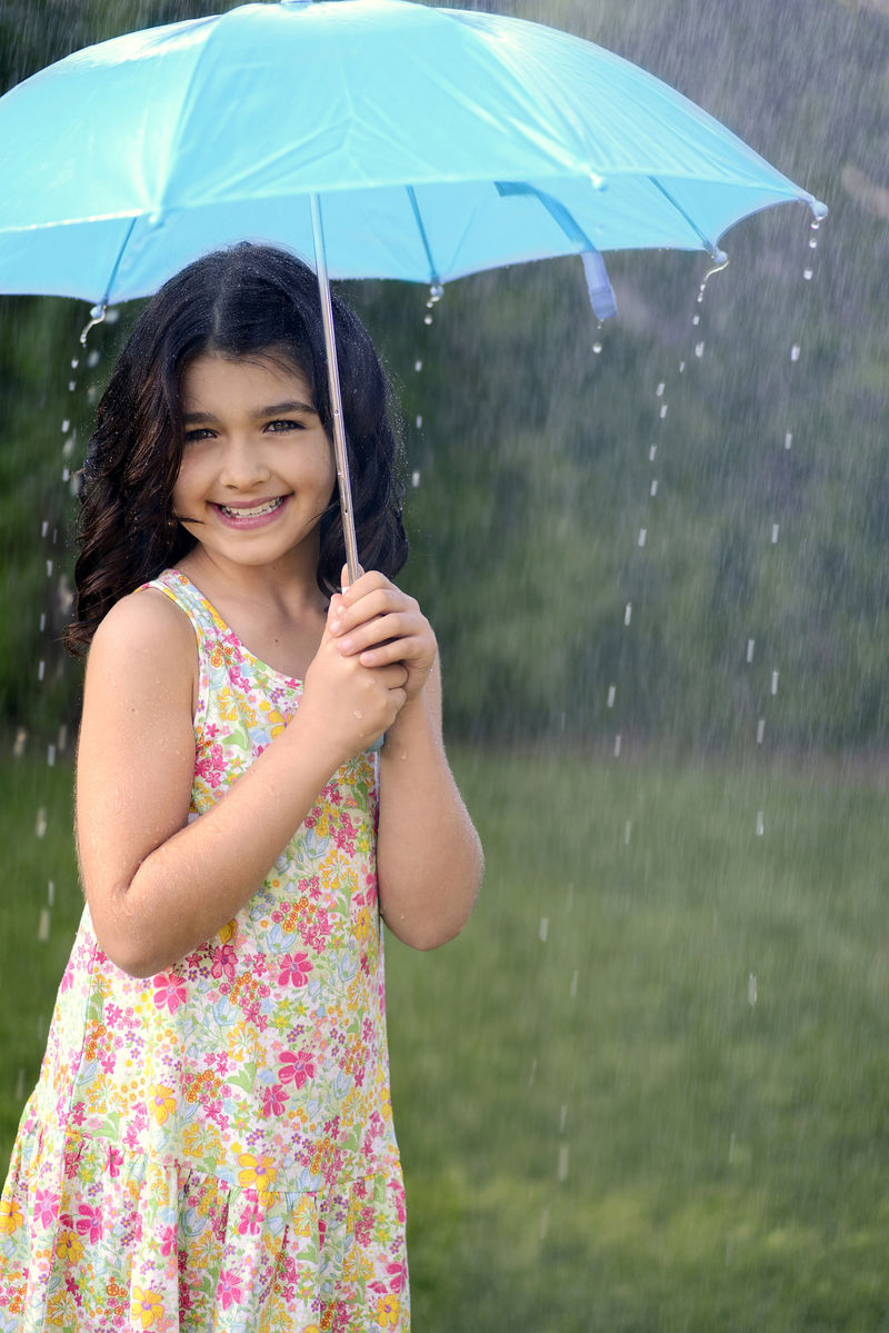 在雨中拿伞玩耍的小女孩