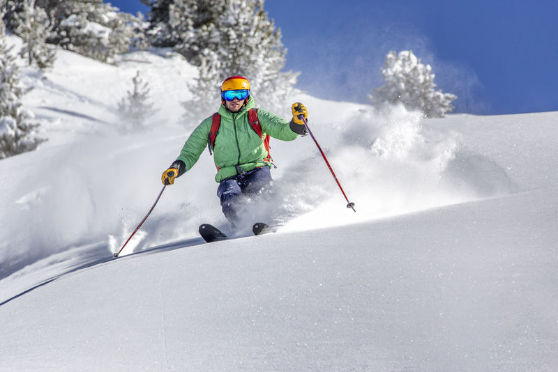 带背包的滑手在新鲜的雪粉上滑雪下坡
