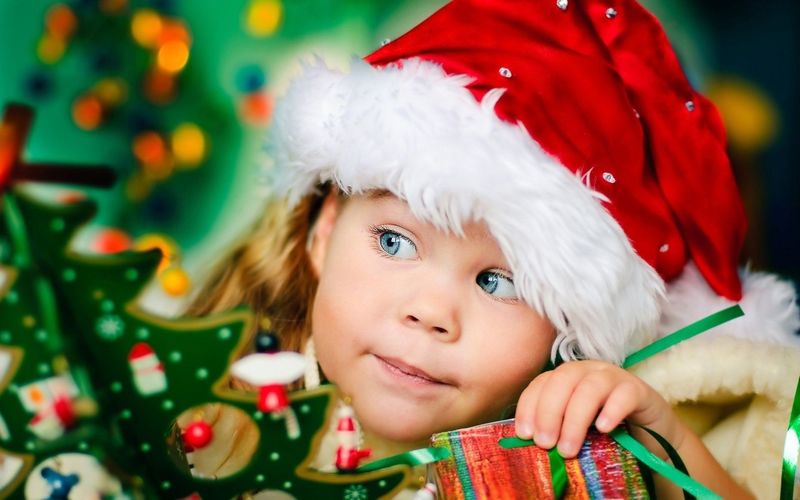 快乐小女孩在圣诞老人的帽子和礼物有一个圣诞节