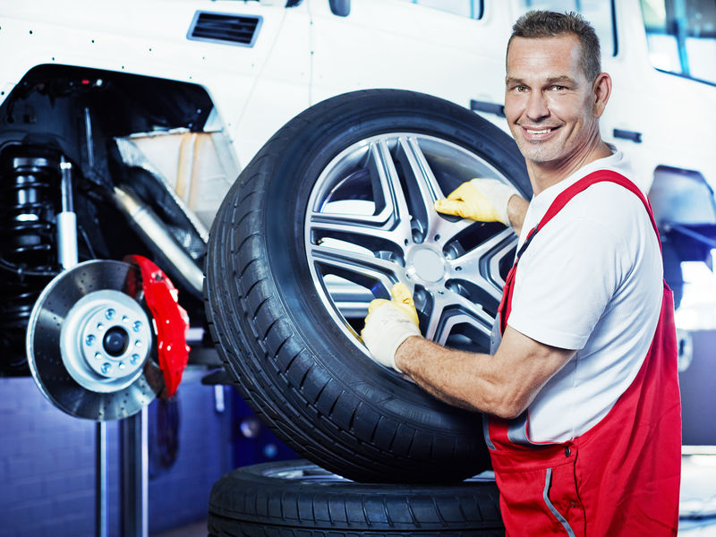 汽车修理工用新的铝轮辋更换轮胎