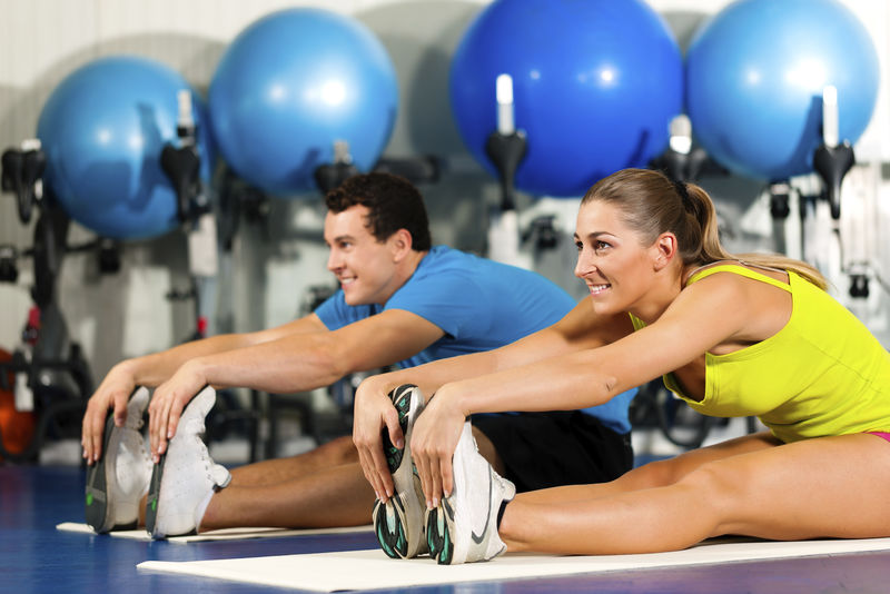 两人穿彩色衣服在健身房做有氧运动或热身体操和伸展运动
