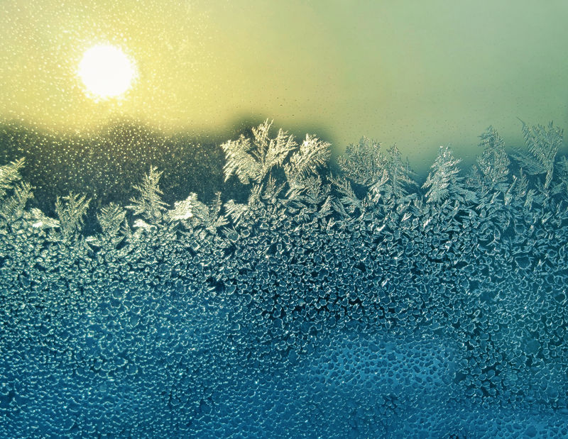 冬季玻璃上的霜冻自然图案和阳光